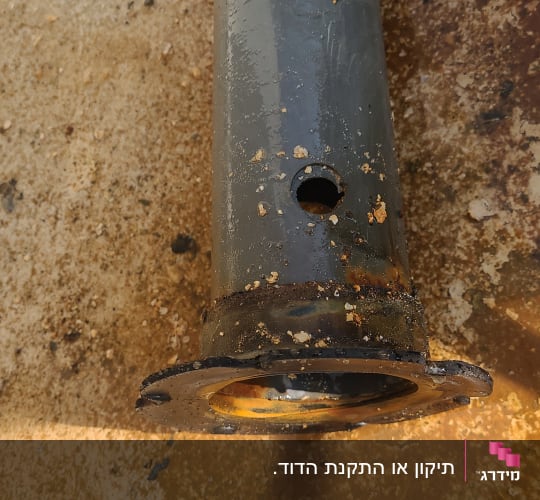 צינור מתכת עם חור ולכלוך על הקרקע
